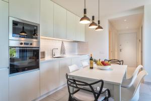 a white kitchen with a white table and chairs at Luxurious & Premium Flat - Pool & Gym in Tavira