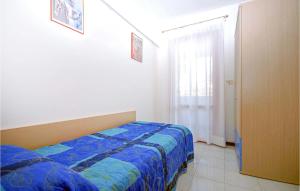 sypialnia z łóżkiem z niebieską kołdrą i oknem w obiekcie Holiday Village w Lignano Sabbiadoro