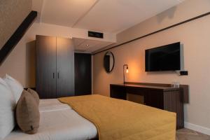 a hotel room with a bed and a flat screen tv at Grand Hotel Beatrix in Den Helder +46 photos