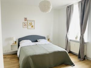 a white bedroom with a bed with a green blanket at aday - The Swanky Suite in Hjørring