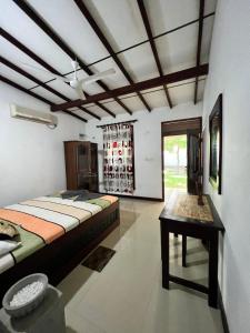 Sylvester Villa Hostel Negombo في نيجومبو: غرفة نوم فيها سرير وطاولة فيها