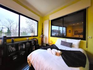 a bedroom with two beds and two large windows at 360 : Superbe maison, rooftop, vue Tour Eiffel, T2 in Meudon