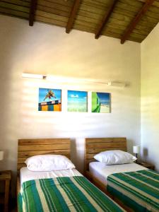 a bedroom with two beds and paintings on the wall at Mabouya chez Villas Piment Café in Deshaies