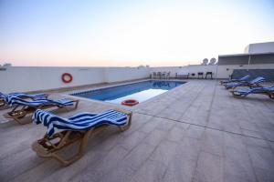 a swimming pool with lounge chairs and a swimming pool at BW Suites & Spa in Juffair