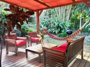 a hammock on a deck with chairs and a table at Mabouya chez Villas Piment Café in Deshaies