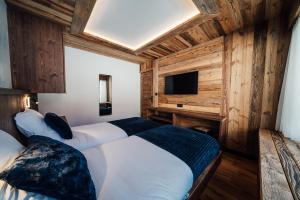 twee bedden in een kamer met houten wanden en een televisie bij Appartement Pixel by ExplorHome in Tignes