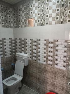 łazienka z toaletą i ścianą wyłożoną kafelkami w obiekcie Shri Gamya Guest House w mieście Ujjain