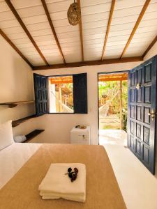 a bedroom with a bed and a large window at Pousada Vilarejo in Caraíva