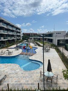 una piscina del resort con tavoli e sedie e un parco giochi di Makia Flat Muro Alto a Porto De Galinhas