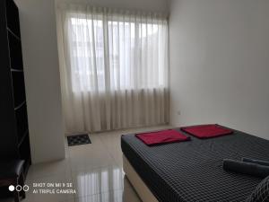 ein Schlafzimmer mit einem Bett mit zwei roten Kissen darauf in der Unterkunft Pool Smart Tv Wifi 3 aircond room Jitra Kolej Height Utara in Jitra