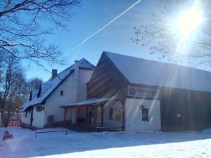 a building in the snow with the sun behind it at Penzion U dvojice in Nové Město na Moravě