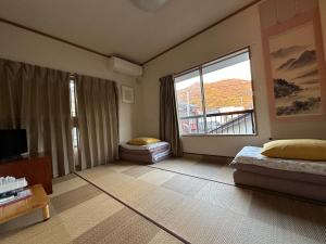 Cette chambre comprend un lit et une grande fenêtre. dans l'établissement Numazu Ikyuuan 沼津一休庵, à Numazu