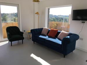 a living room with a blue couch and a chair at Beautiful home with stunning lake and valley views in East Harptree