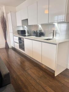 een keuken met witte kasten en een houten vloer bij Ideal for Contractors in Reading with Free Parking in Reading