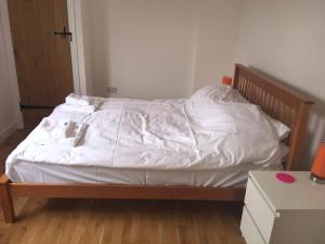 an unmade bed with white sheets on it in a room at Beautiful home with stunning lake and valley views in East Harptree