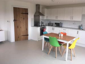 a kitchen with a wooden table and colorful chairs at Beautiful home with stunning lake and valley views in East Harptree