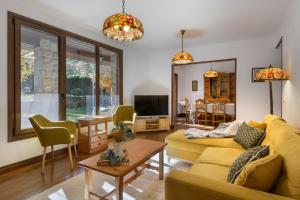 a living room with a yellow couch and a tv at Villa Lana chalet Baros, Jaca in Jaca