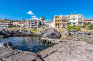 een waterlichaam met gebouwen op de achtergrond bij Seafront Apt with View in Aci Castello in Aci Castello