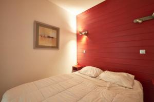a bedroom with a red wall and a white bed at Bulle enchantée lac et montagne in Allevard