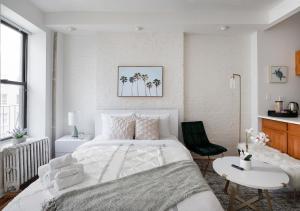 a white bedroom with a large bed and a table at Beautiful Studio Apartment At East Side in New York