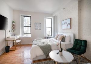 a white bedroom with a bed and a green chair at Beautiful Studio Apartment At East Side in New York