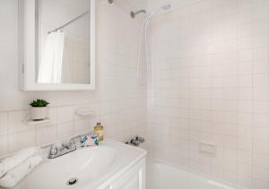 a white bathroom with a sink and a mirror at Beautiful Studio Apartment At East Side in New York