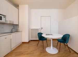 una cucina con tavolo bianco e due sedie verdi di Amazing studio in San Babila a Milano