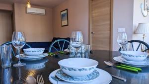 a wooden table with bowls and plates and wine glasses at GALEON sea view apartment in Benidorm