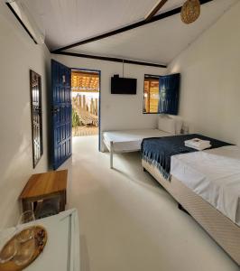 a bedroom with a bed and a table and a window at Pousada Vilarejo in Caraíva