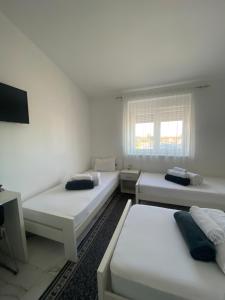 a white room with three beds and a tv at Vila Safir in Loznica