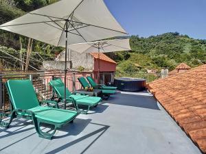 três cadeiras verdes e um guarda-sol num pátio em Casa Avo Maria by Atlantic Holiday em São Vicente