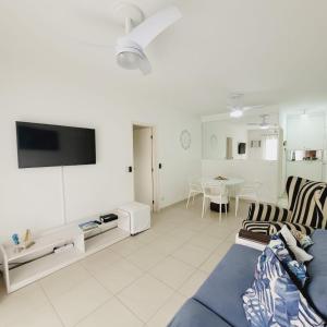 een woonkamer met een blauwe bank en een tv bij Apartarmento Ar Con - WIFI - Garagem - Piscina - Enseada Guarujá in Guarujá