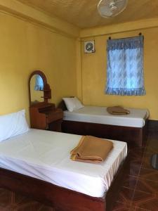 two beds in a room with a mirror and a window at Somewhere over the river in Ban Houayxay