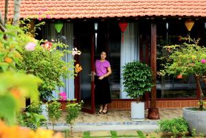 une femme debout à l'entrée d'une maison dans l'établissement Ngoc Lan Homestay 2, 