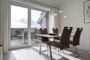 a dining room with a table and chairs and a balcony at LM9-3-3 - Ferienwohnung Wremer Bogen Komfort in Schottwarden