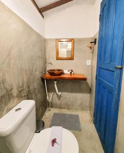 a bathroom with a white toilet and a blue door at Pousada Vilarejo in Caraíva