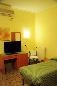 a bedroom with a bed and a desk with a television at Albergo Casa Lupi in Guidonia