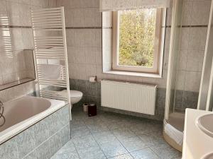 La salle de bains est pourvue d'une baignoire, de toilettes et d'une fenêtre. dans l'établissement Taos B&B, à Vresse-sur-Semois