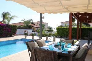 un patio con mesa y sillas junto a una piscina en Villa Niki, en Ayia Napa