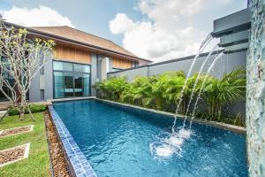 a swimming pool with a fountain in front of a house at Saiyuan Estate by TropicLook in Rawai Beach