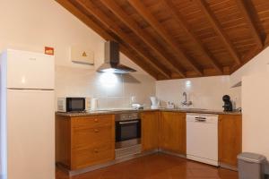 a kitchen with wooden cabinets and a white refrigerator at By the hill in Ribeira Grande