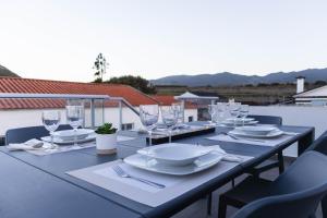 una mesa con platos y copas de vino en el balcón en By the hill, en Ribeira Grande