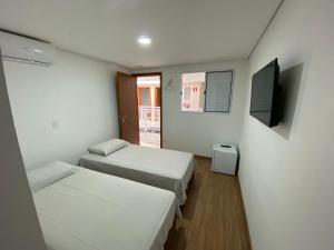 a room with two beds and a flat screen tv at Pousada Vila Barboza - Próxima ao Thermas Water Park in Águas de São Pedro