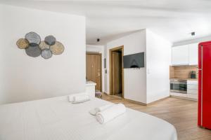 ein weißes Schlafzimmer mit einem weißen Bett und einer Küche in der Unterkunft Elia Kolonaki Luxury Apartments in Athen