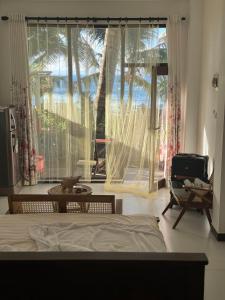 a bedroom with a bed and a large window at Coconut Palm beach restaurant and rooms in Dickwella