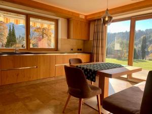 a kitchen with a table and chairs and a large window at Casa Mariella - Apartment with garden in Tesero