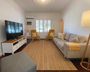 a living room with a couch and a flat screen tv at Sunshine Shack in Wannanup