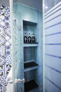 ein Badezimmer mit vier Flaschen Alkohol auf Regalen in der Unterkunft A3_Aplotaria Architect's Apartment in Chios