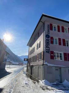 a building in the snow with the sun in the background at Alpina Einhorn - Self-Check-In in Wolfenschiessen