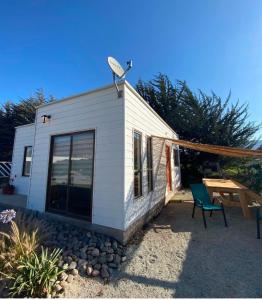 a small white house with a bench and a satellite at Fogones del Valle in Las Rojas